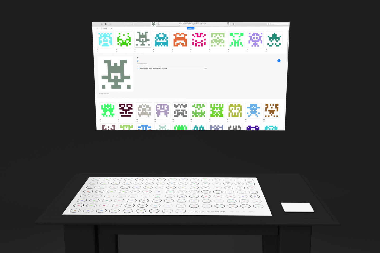 a mockup of the exhibit setup. A projector is setup with an interface for selecting songs. The artist names have been omitted and the album art consists of computer generated pixel art. There is a table with a sheet of paper which contain audio waveforms of songs combined with their pixel art. Besides the sheet of paper is a wireless trackpad.